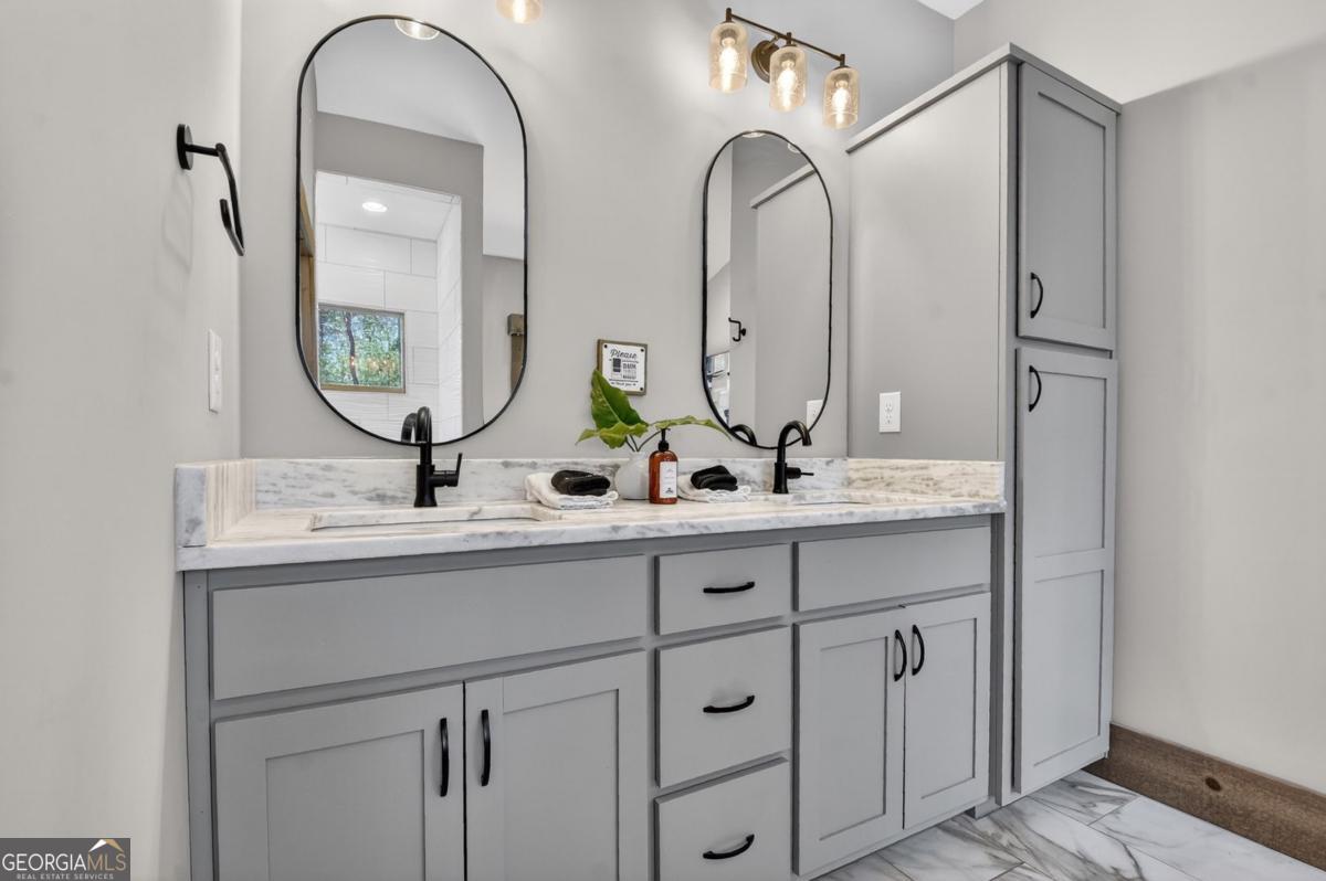 466 Watersong Bluff West Ellijay, GA 30540 - Photo 33 of 67 a bathroom with double vanity sinks a vanity a mirror and a wooden floor