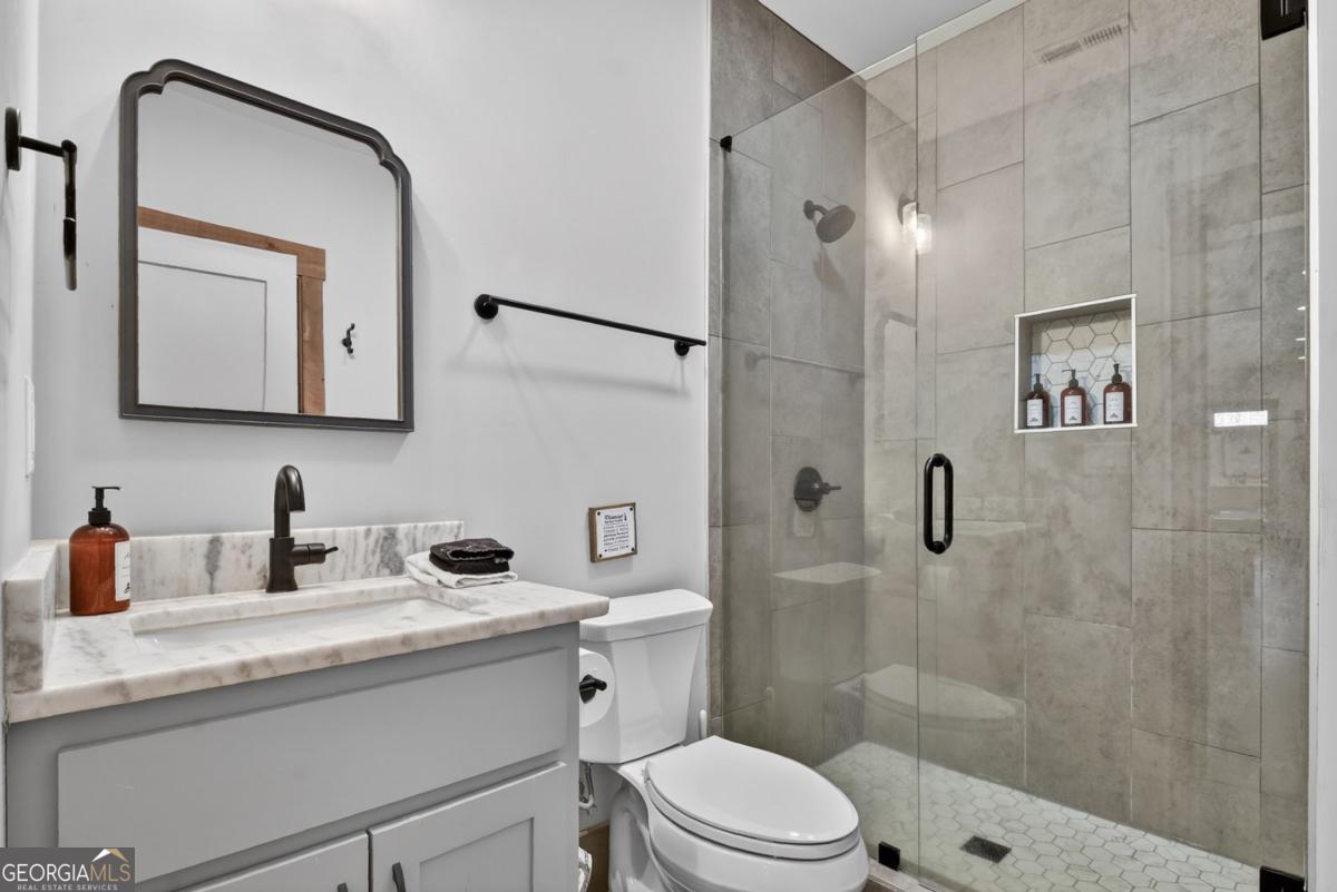 466 Watersong Bluff West Ellijay, GA 30540 - Photo 53 of 67 a bathroom with a granite countertop sink a mirror a shower and a toilet