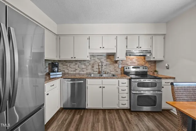 a kitchen with white cabinets and stainless steel appliances