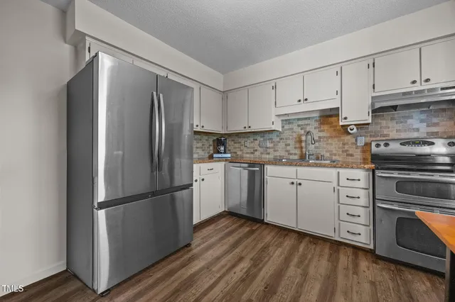a kitchen with white cabinets stainless steel appliances and wooden floor