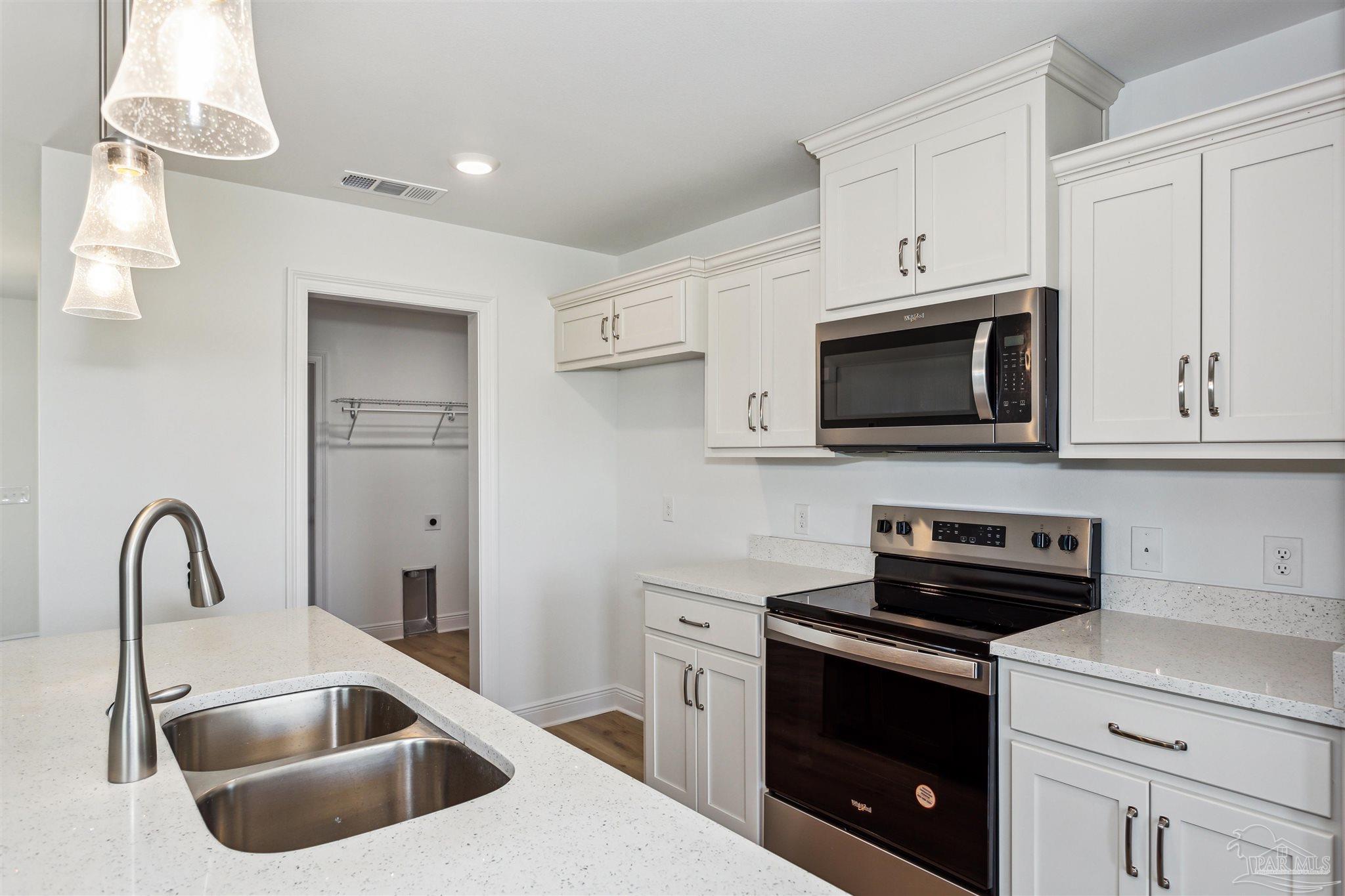9319 Salter Road Pace, FL 32571 - Photo 11 of 32 a kitchen with white cabinets a sink and a stove with wooden floor