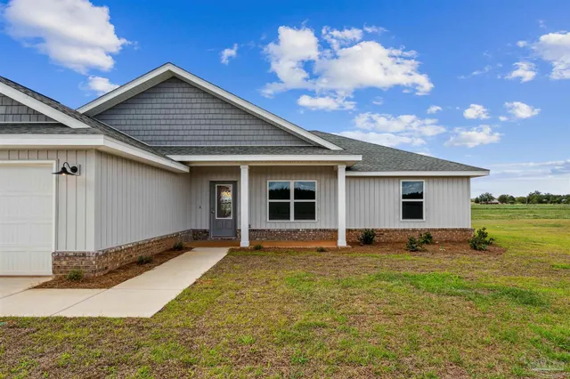a front view of house with yard and trees in the background