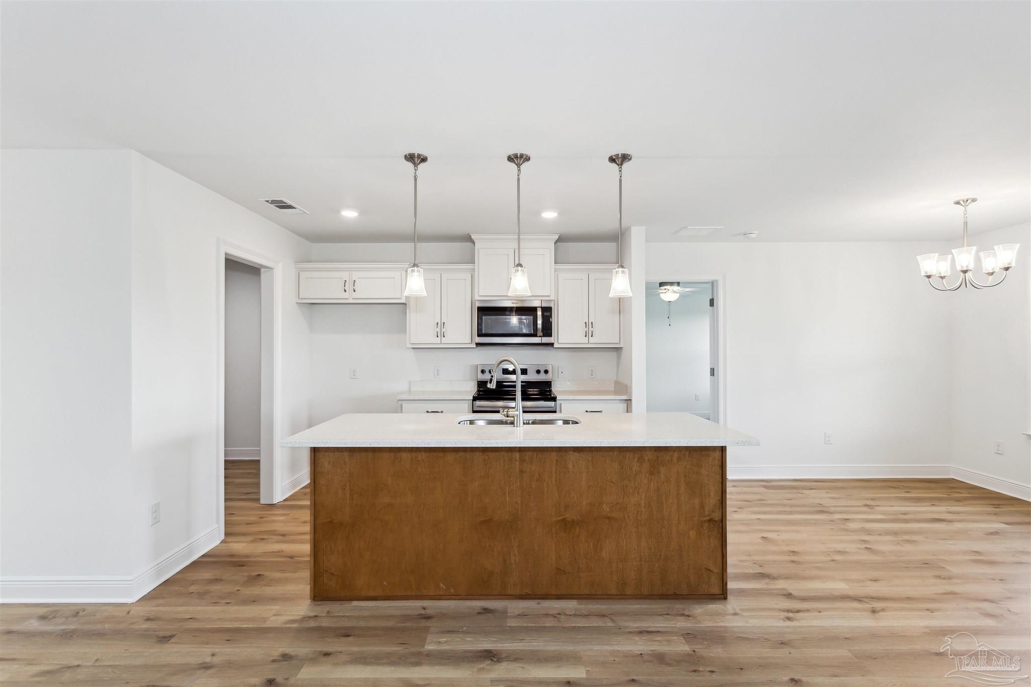 9319 Salter Road Pace, FL 32571 - Photo 8 of 32 a view of a kitchen with kitchen island a sink wooden floor and a refrigerator