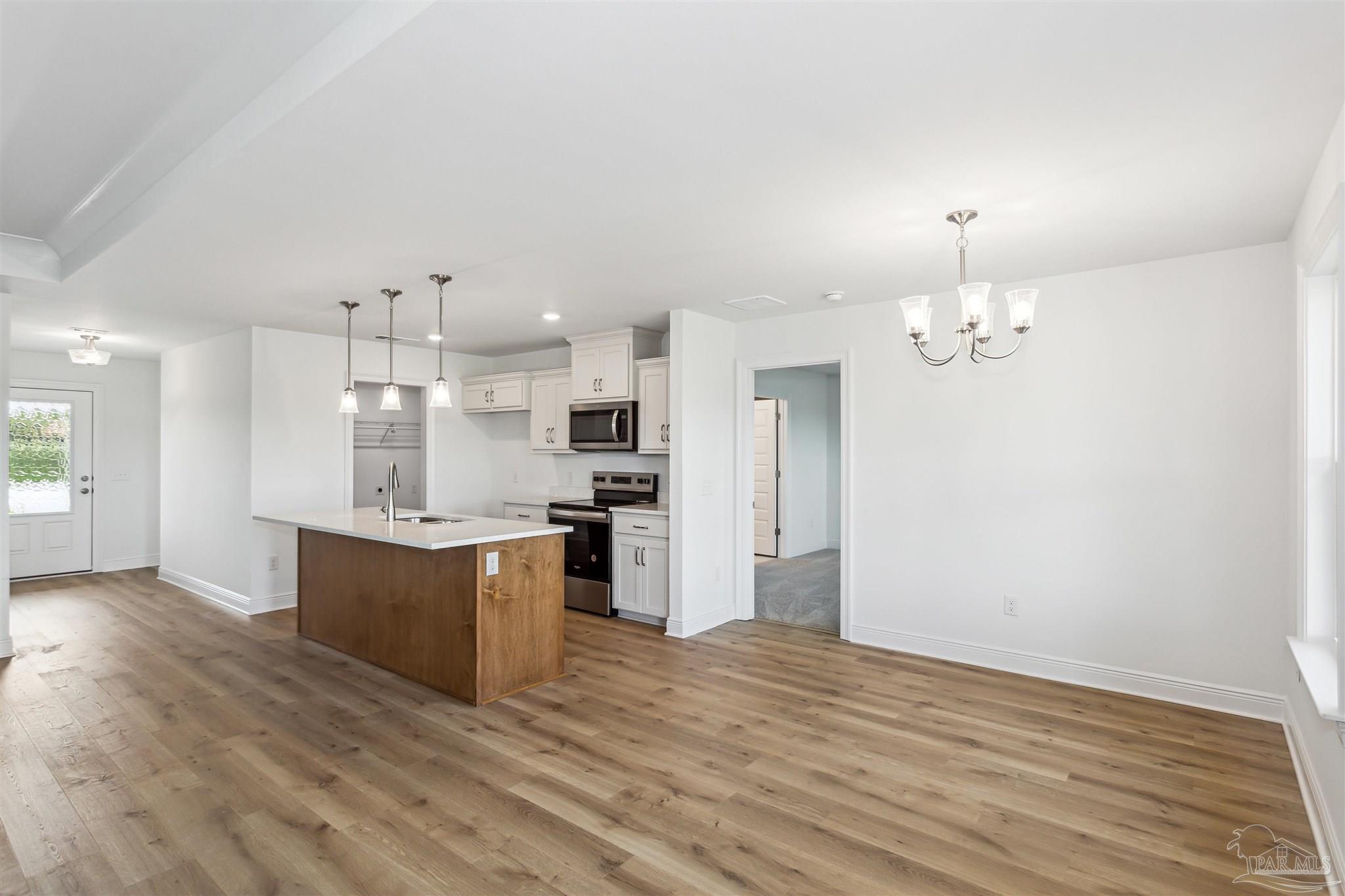 9319 Salter Road Pace, FL 32571 - Photo 9 of 32 a large kitchen with kitchen island a sink stainless steel appliances and cabinets