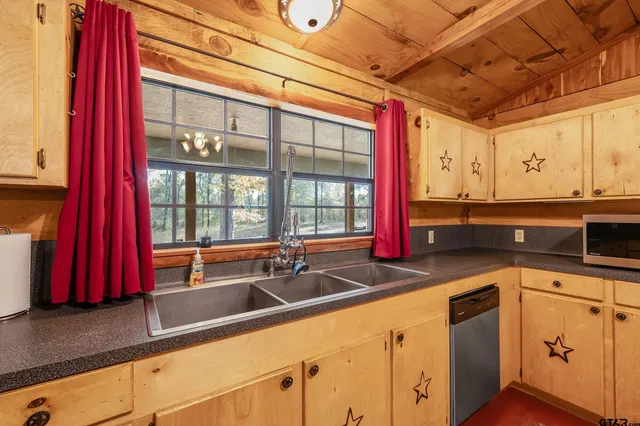 a utility room with stainless steel appliances granite countertop a sink a stove and cabinets