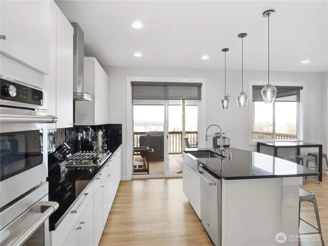 a large kitchen with stainless steel appliances granite countertop a sink a stove and a wooden floors