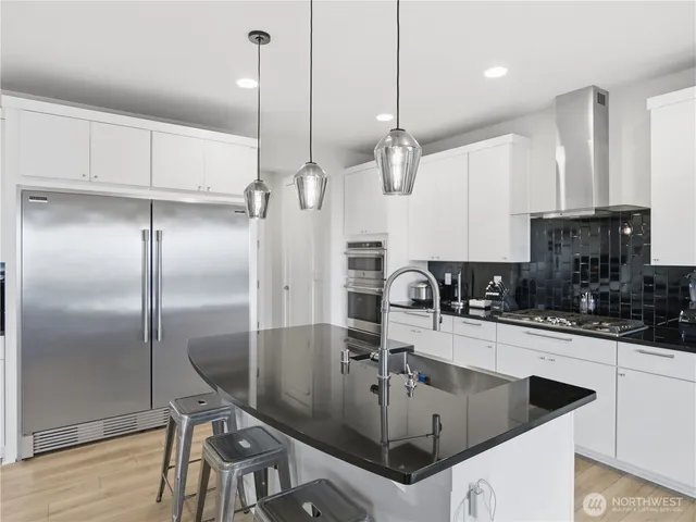 a kitchen with stainless steel appliances granite countertop a sink a refrigerator and cabinets