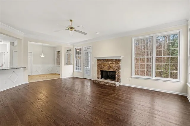 a view of an empty room with wooden floor fireplace and a window
