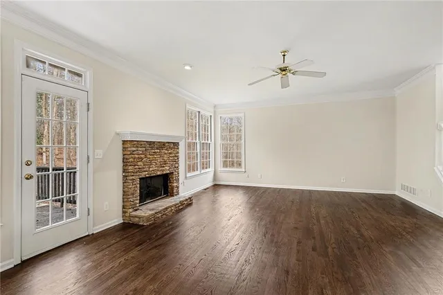 an empty room with windows fireplace and wooden floor