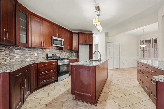 a kitchen with stainless steel appliances granite countertop wooden cabinets a stove top oven a sink and dishwasher