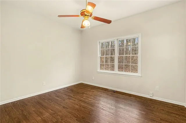 an empty room with wooden floor fan and windows