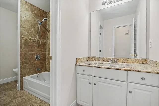 a bathroom with a granite countertop sink and a bathtub