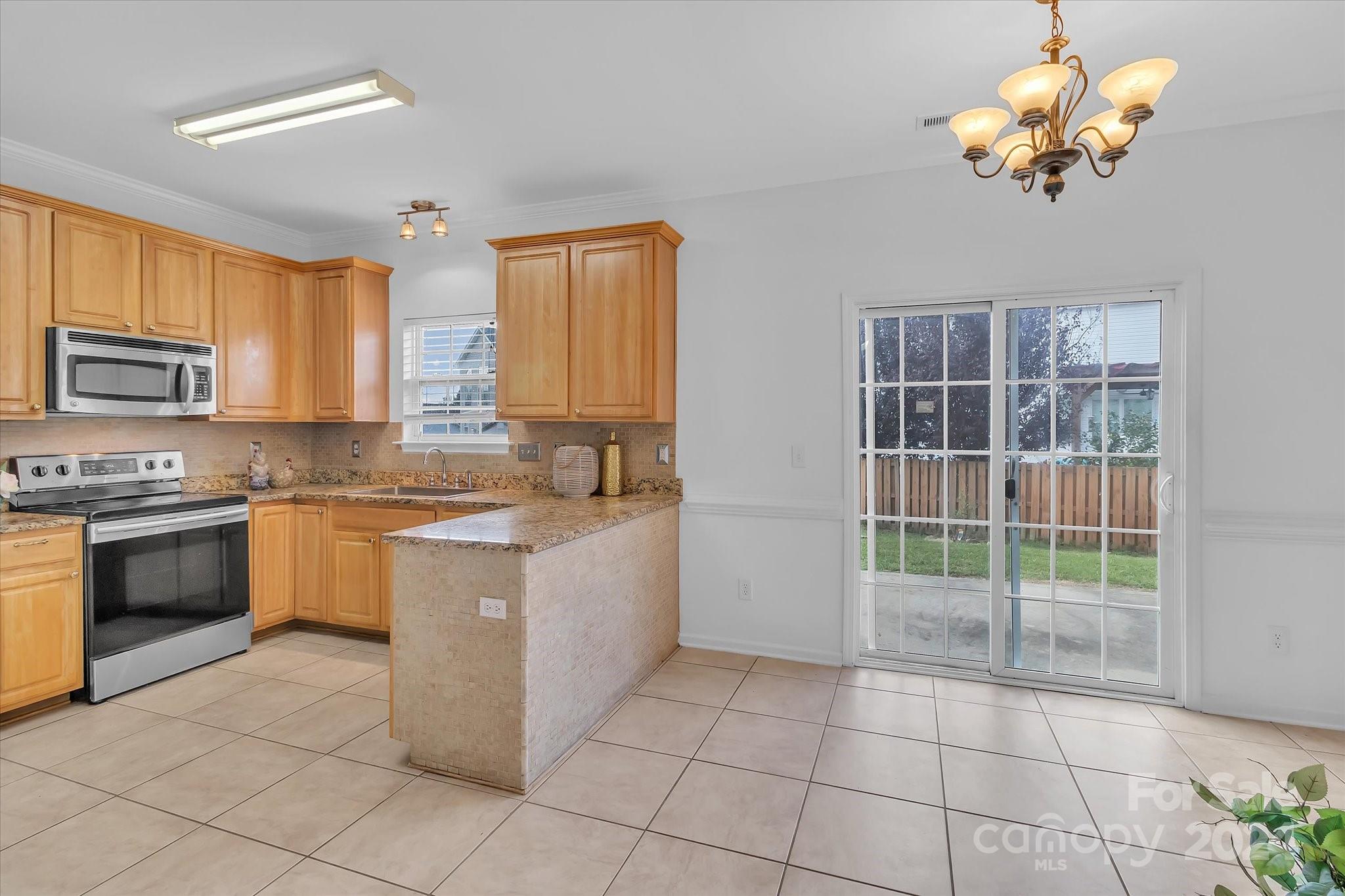1004 Kipling Court Indian Trail, NC 28079 - Photo 12 of 42 a large kitchen with a stove top oven cabinets a dining table and a window