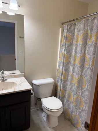 a bathroom with a granite countertop toilet a sink and a mirror