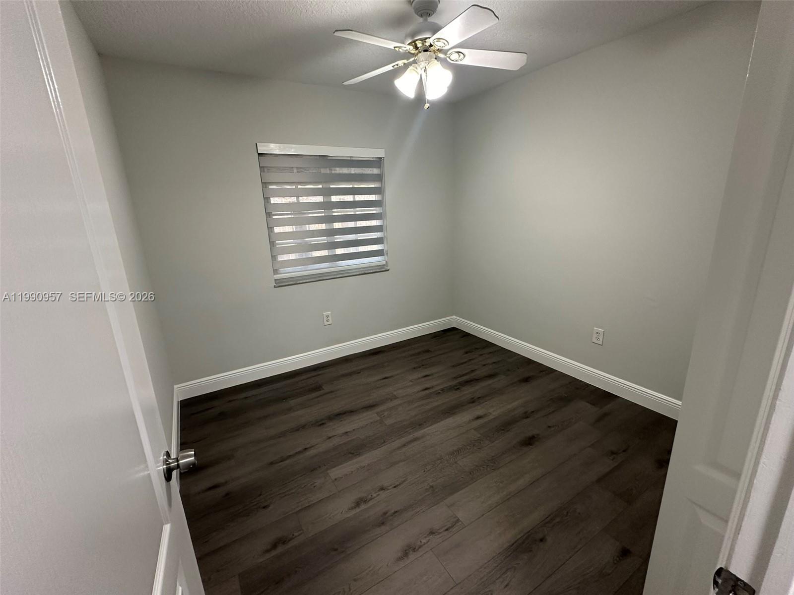 12005 Southwest 14th Street, Unit 403D Miami, FL 33184 - Photo 15 of 26 a view of an empty room with wooden floor and a window