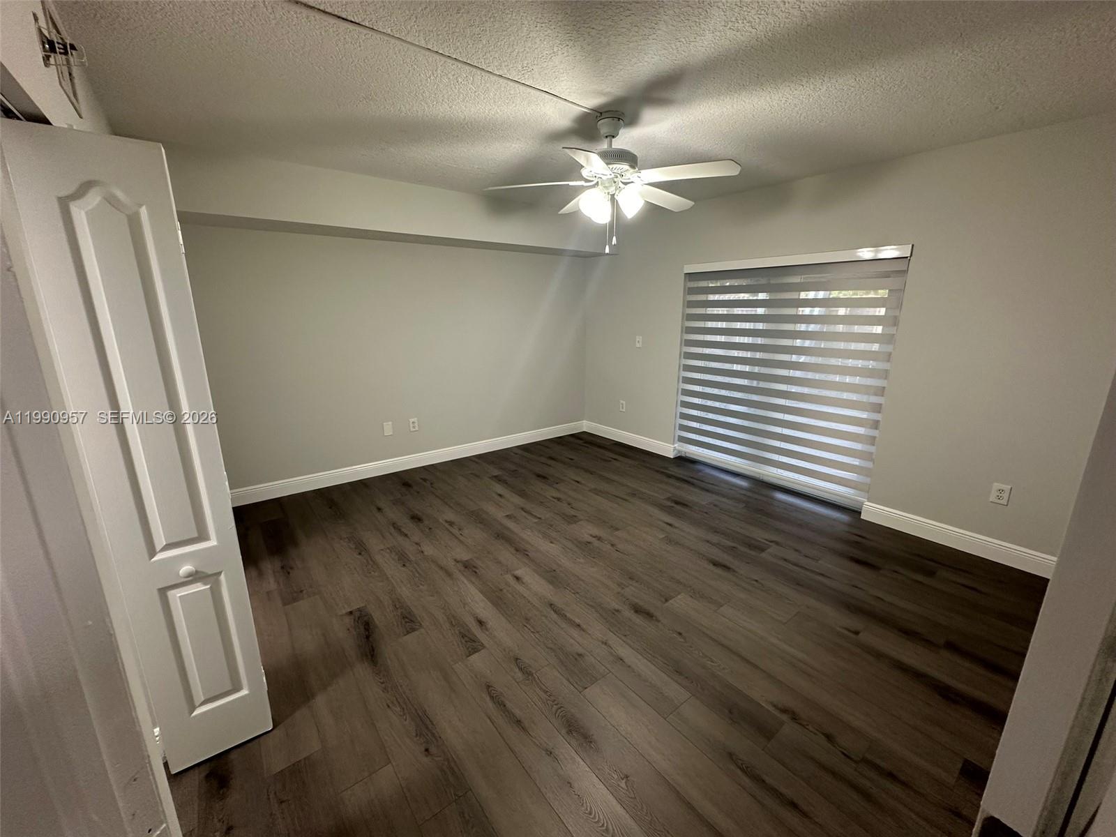 12005 Southwest 14th Street, Unit 403D Miami, FL 33184 - Photo 17 of 26 an empty room with wooden floor and fan