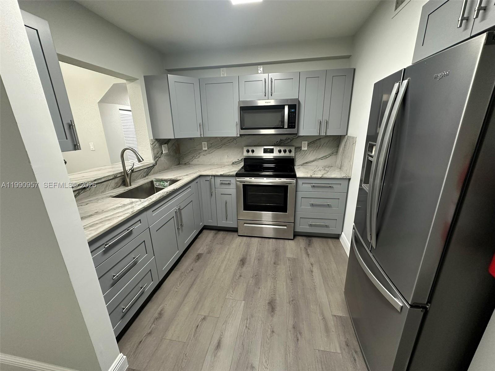 12005 Southwest 14th Street, Unit 403D Miami, FL 33184 - Photo 6 of 26 a kitchen with refrigerator a microwave a sink and cabinets