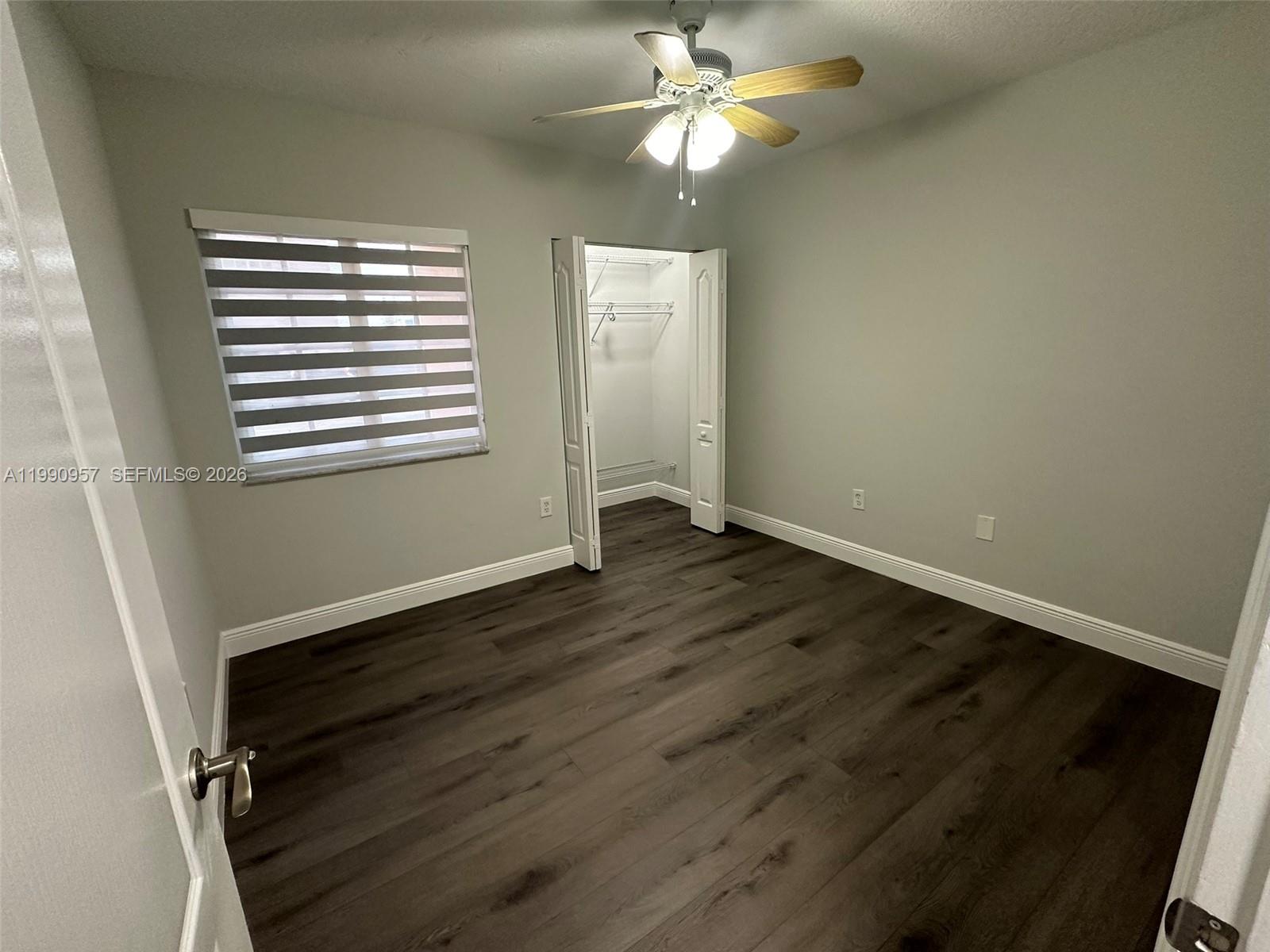 12005 Southwest 14th Street, Unit 403D Miami, FL 33184 - Photo 9 of 26 a view of an empty room with wooden floor and a window