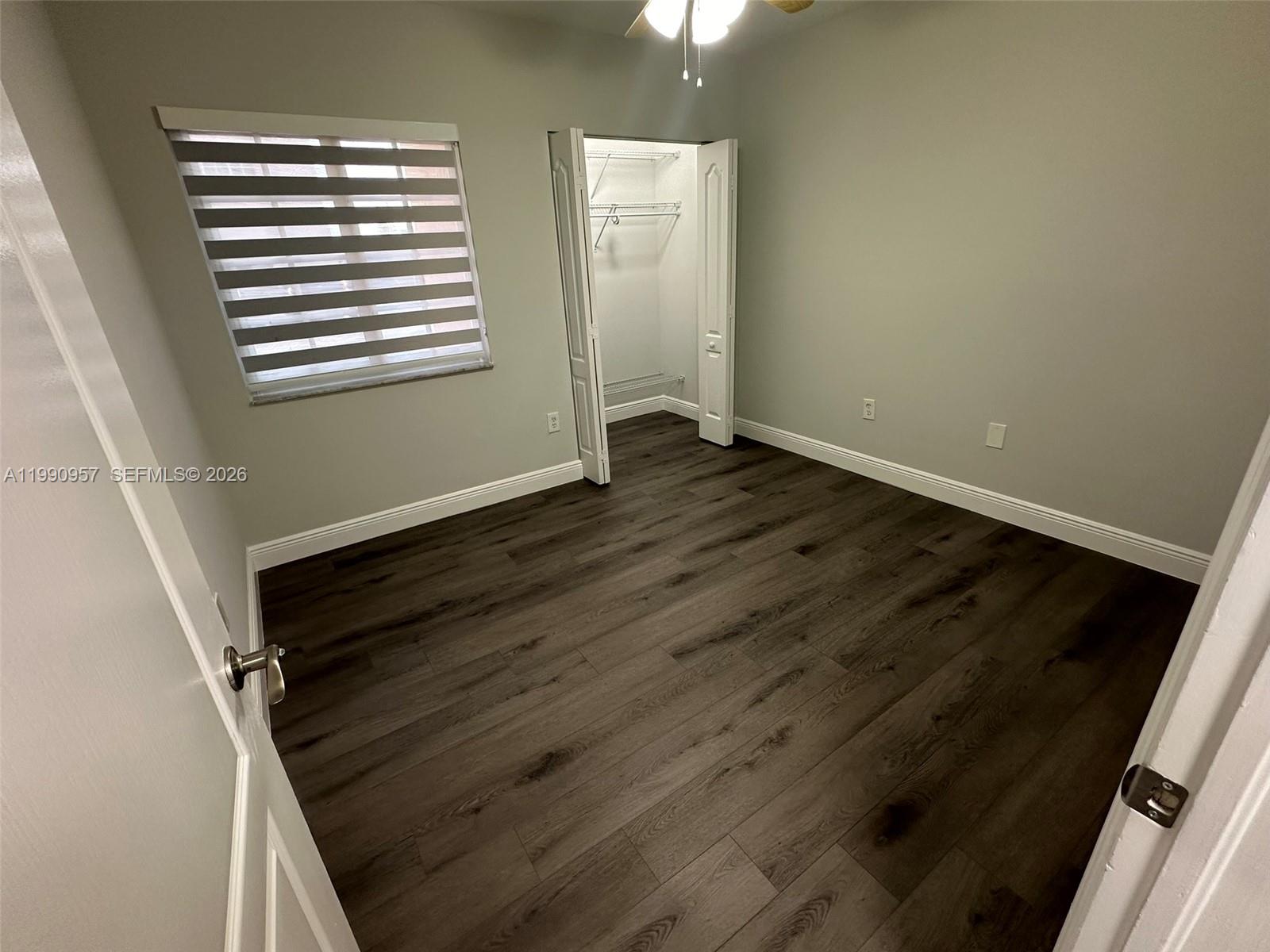 12005 Southwest 14th Street, Unit 403D Miami, FL 33184 - Photo 10 of 26 a view of an empty room with wooden floor and a window