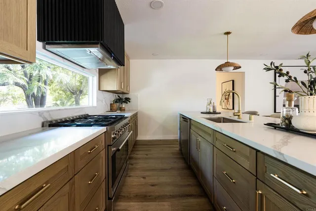 a kitchen with stainless steel appliances granite countertop a sink a stove and a wooden floors