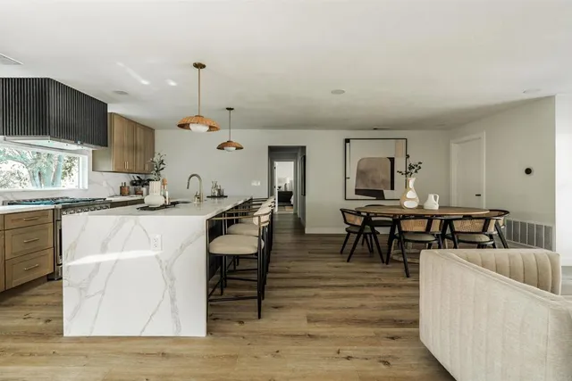 a living room with couches chairs and kitchen view with wooden floor