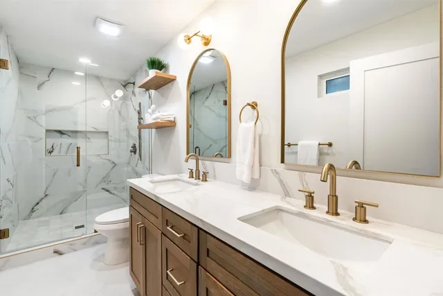 a bathroom with a double vanity sink toilet and shower