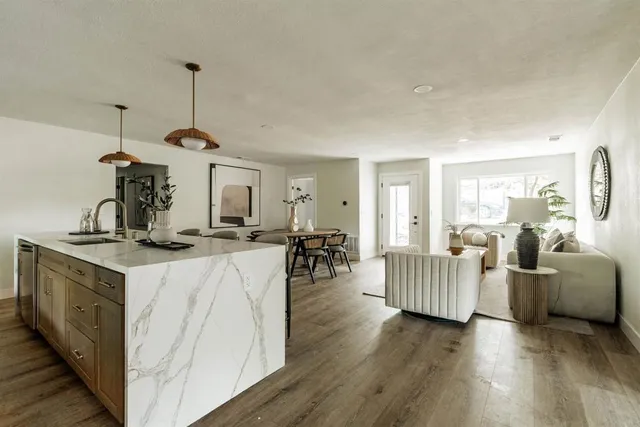 a kitchen with stainless steel appliances granite countertop a sink dishwasher and a stove with wooden floor