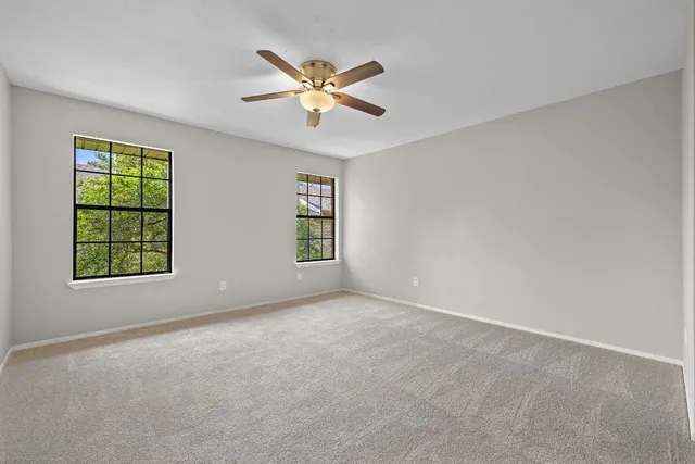 an empty room with windows and fan