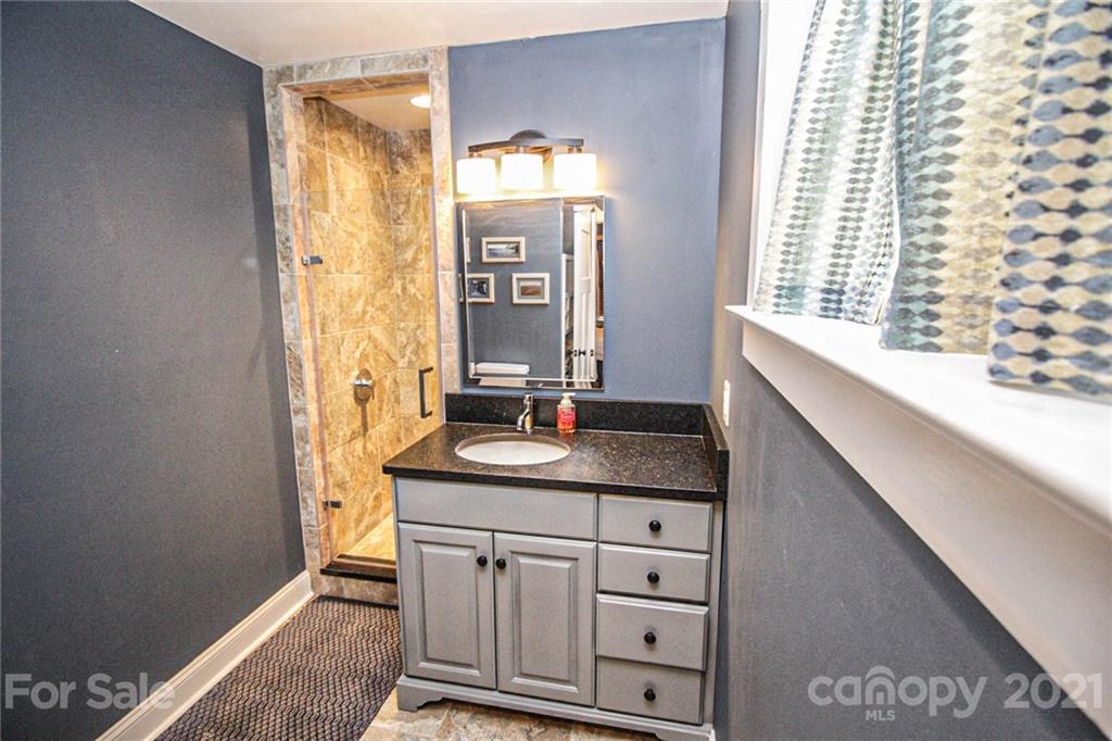 4227 Murrayhill Road Charlotte, NC 28209 - Photo 14 of 24 a bathroom with a granite countertop sink a mirror and a shower