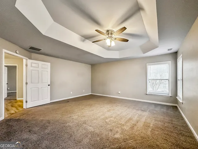 an empty room with windows and ceiling fan