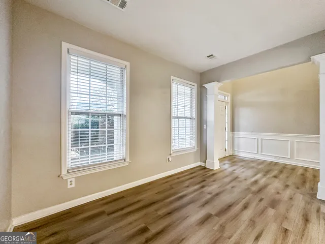 a view of an empty room with wooden floor and a window
