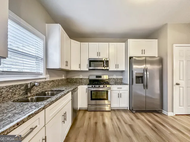 a kitchen with granite countertop a sink stove and refrigerator