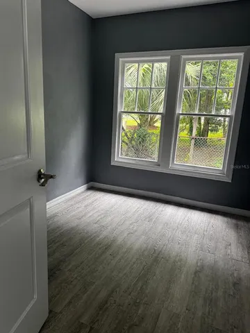 an empty room with wooden floor and windows