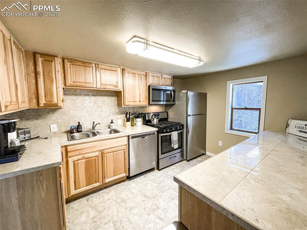 6025 Sioux Trail Cascade, CO 80809 - Photo 15 of 42 a kitchen with granite countertop a stove top oven a sink dishwasher and a refrigerator with wooden cabinets