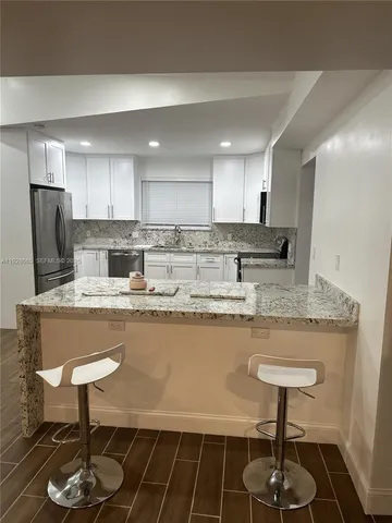 a kitchen with stainless steel appliances granite countertop a stove a sink a refrigerator and a counter space