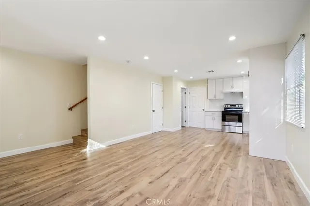 a kitchen with a refrigerator a stove top oven and wooden floor