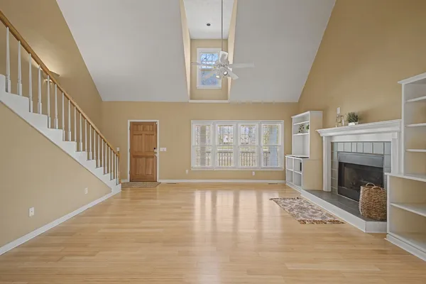 a view of an empty room with wooden floor fireplace and a window