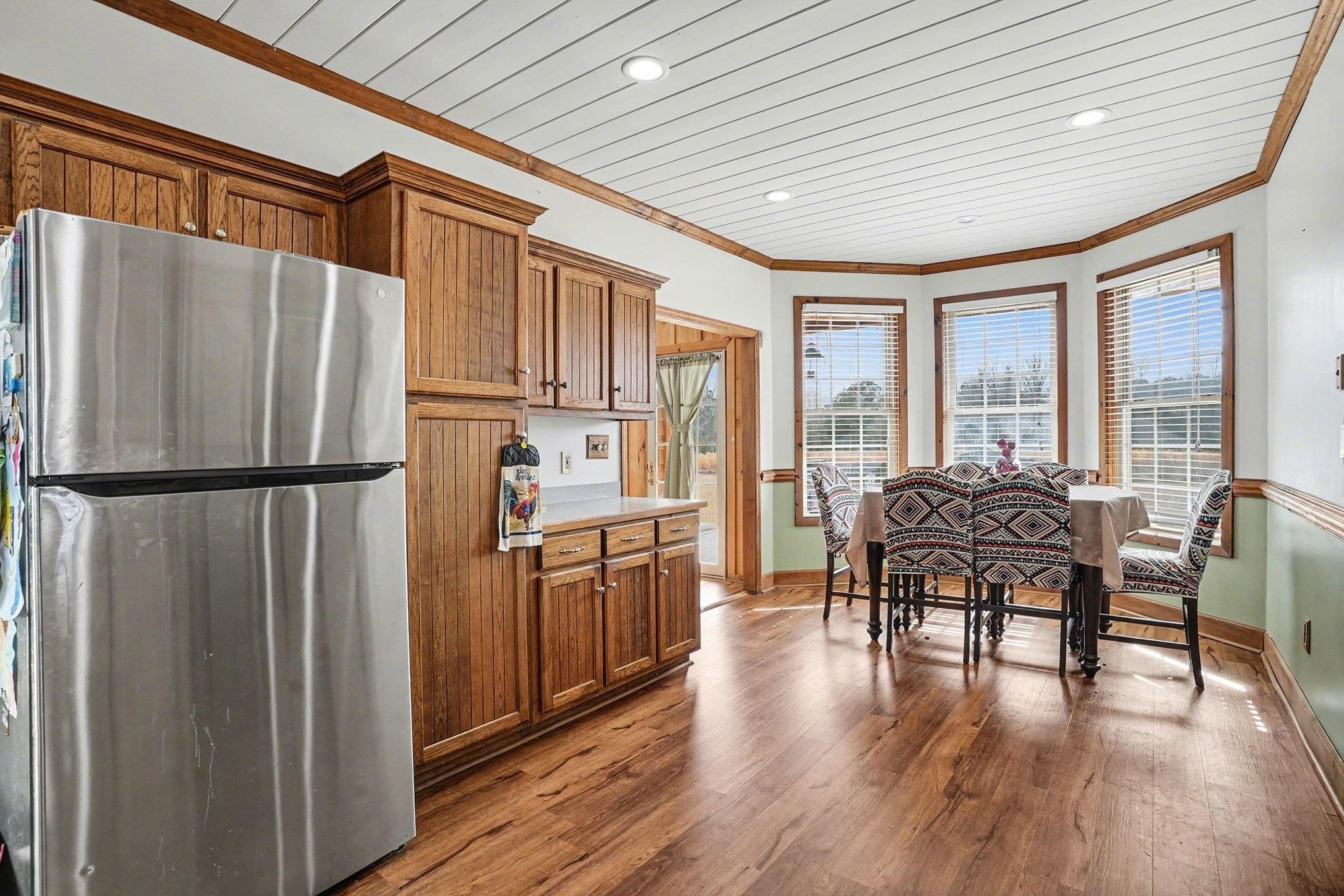 202 Highway 747 Loris Sc 29569 Loris, SC 29569 - Photo 11 of 34 Kitchen with freestanding refrigerator, brown cabinetry, crown molding, dark wood-style flooring, and light countertops