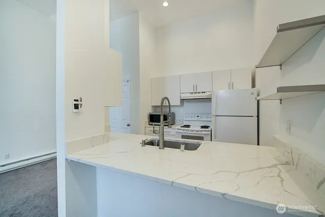 a kitchen with kitchen island a sink a stove a refrigerator and white cabinets