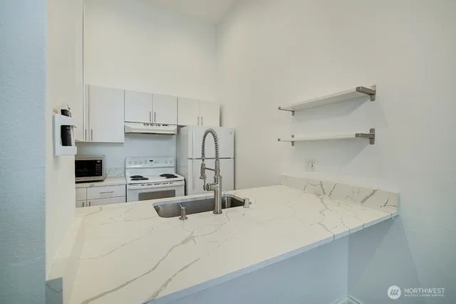 a kitchen with kitchen island a sink a stove and white cabinets