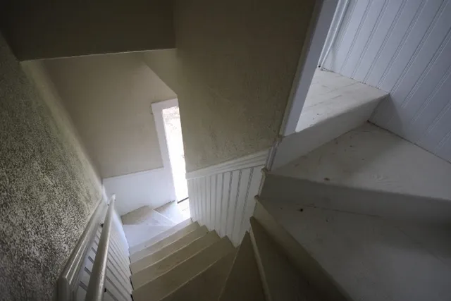 a view of staircase with white walls and door