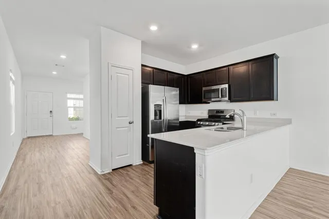 a kitchen with a refrigerator a stove and a microwave oven with wooden floor