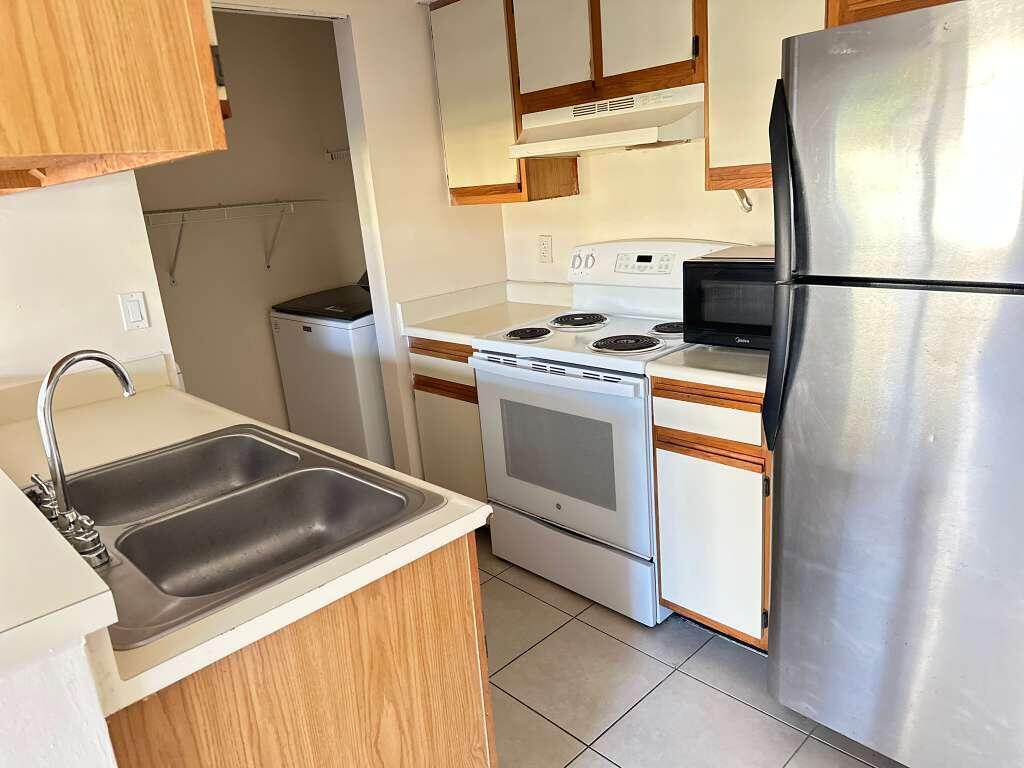 1239 Southwest 46th Avenue, Unit 906 Pompano Beach, FL 33069 - Photo 9 of 23 a kitchen with stainless steel appliances a refrigerator sink and stove