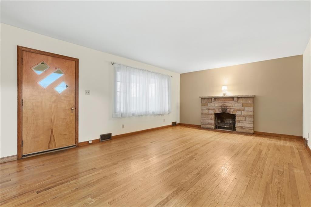 123 Wampum Road Wampum, PA 16157 - Photo 11 of 33 an empty room with wooden floor fireplace and windows
