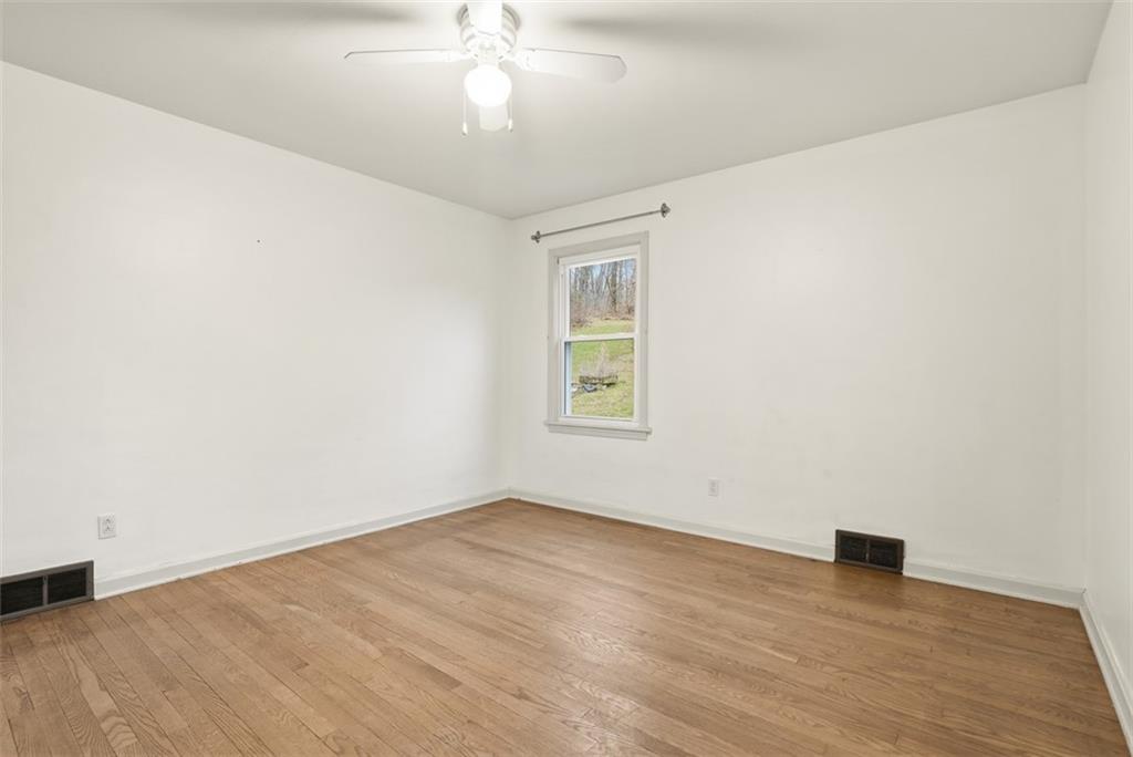 123 Wampum Road Wampum, PA 16157 - Photo 14 of 33 an empty room with wooden floor chandelier fan and windows