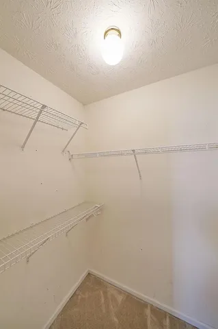 an empty room with a chandelier fan and windows