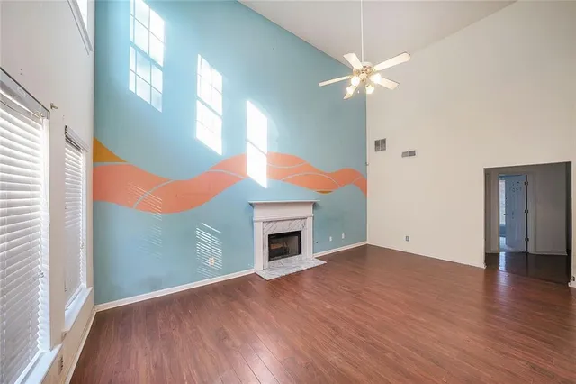 an empty room with wooden floor fan and windows