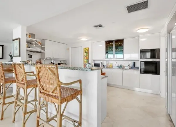 a kitchen with stainless steel appliances kitchen island granite countertop a refrigerator and cabinets