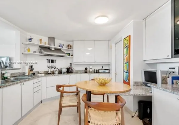 a kitchen with stainless steel appliances kitchen island granite countertop a table chairs sink and cabinets