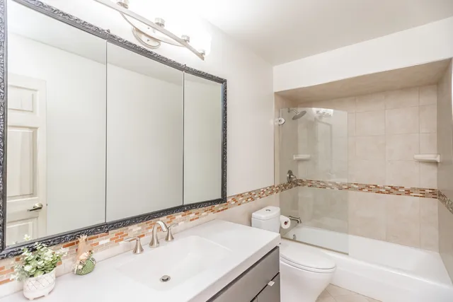 a bathroom with a bathtub shower sink vanity and toilet